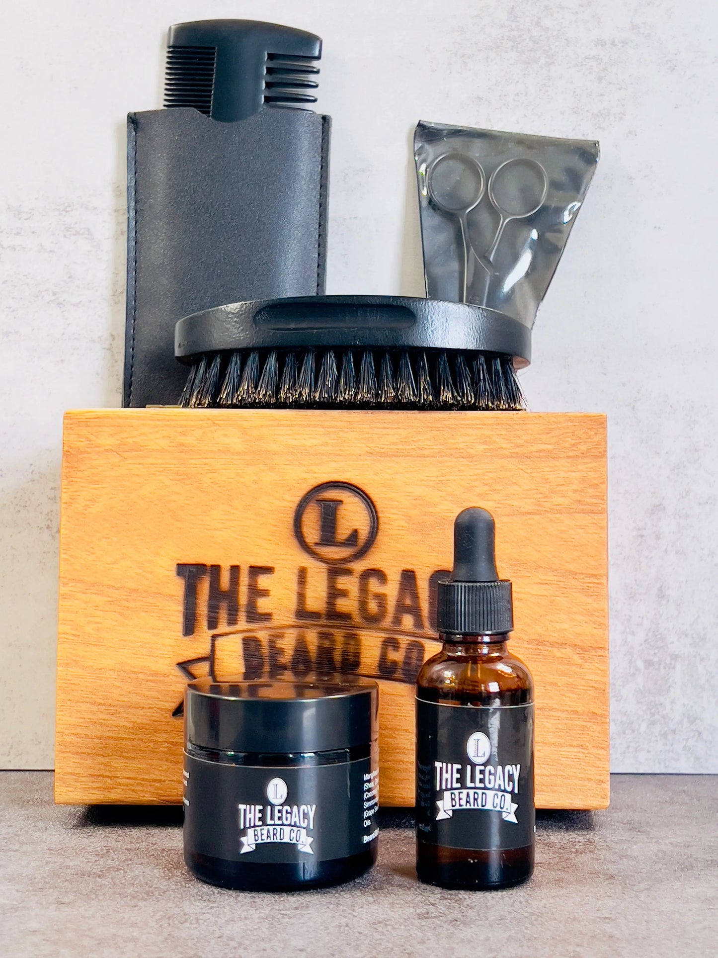 Set of grooming products with 'The Legacy Beard’ branding on a wooden box. Beard Kit Package includes a Beard Oil 1 FL. OZ,
Beard Enhancer 3 FL. OZ, Boar Bristle Beard Brush, Wooden Beard Comb, Stainless Steel Scissors, and Keepsake Wooden Box.