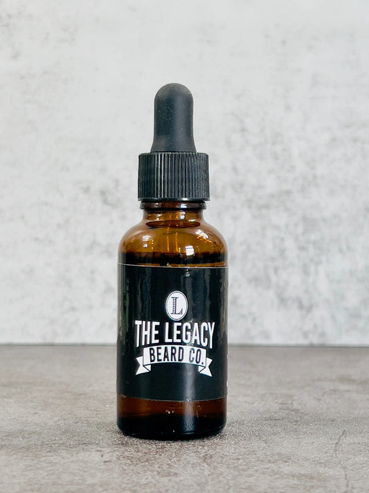 Bottle of The Legacy Beard Co. product on a textured surface with a light gray background