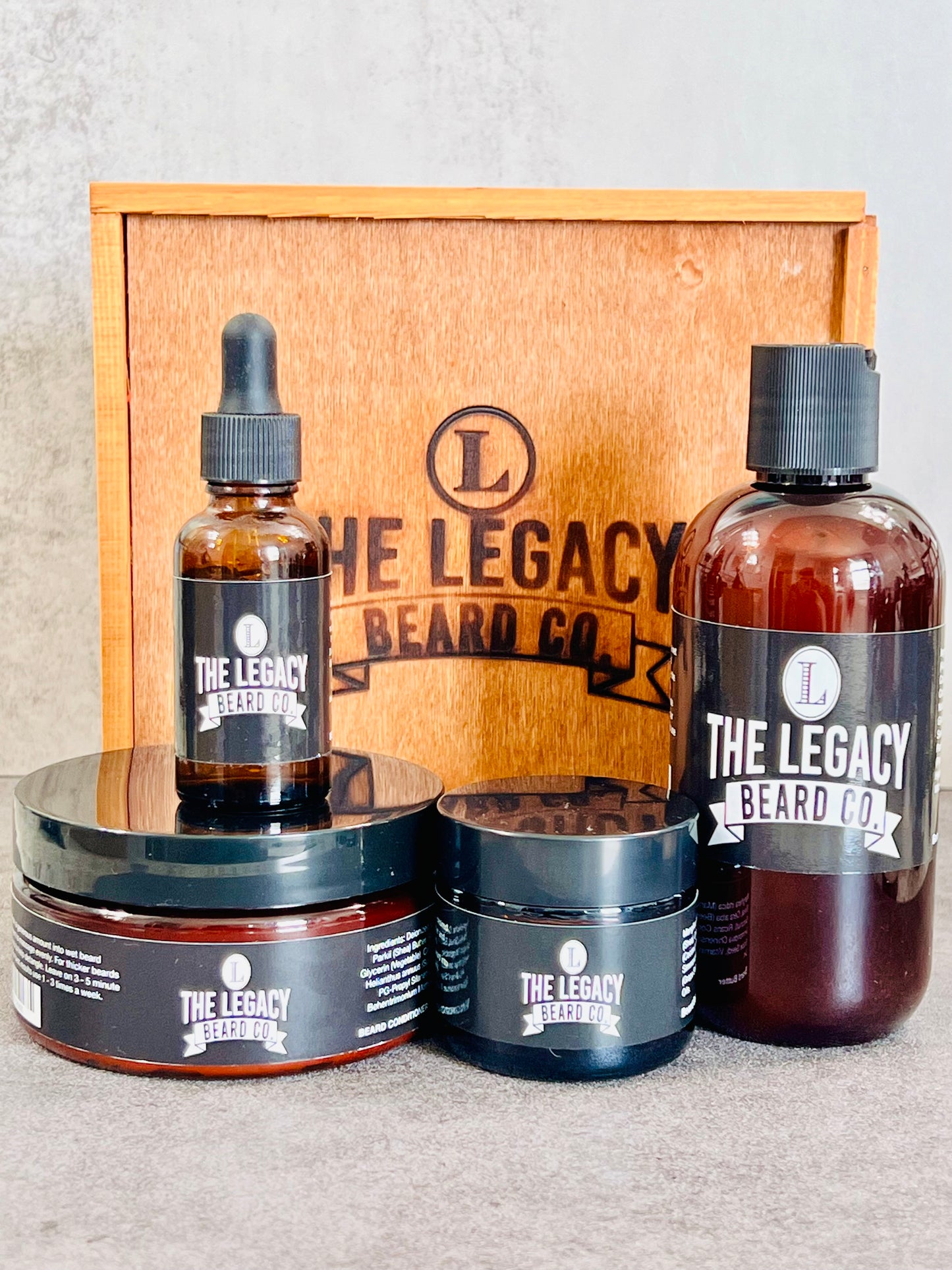 Beard kit wil a white background on a concrete surface. This Kit includes:8 oz. Beard Wash, 8 oz., Beard Conditioner, 3 oz. Beard Enhancer, 1 oz. Beard Oil, Wood keepsake box