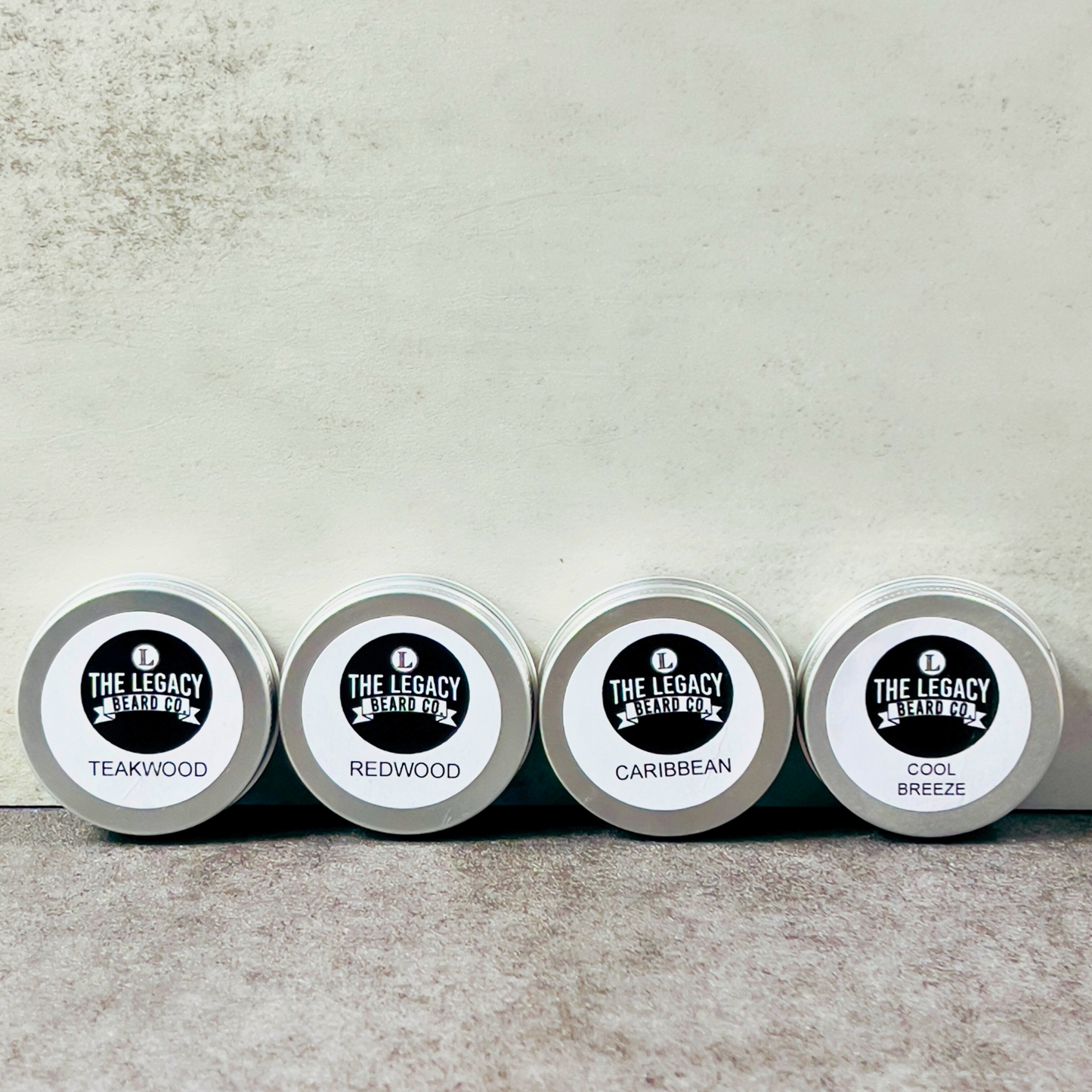 Four tins of 'The Legacy Beard Co.' with different scents on a neutral background