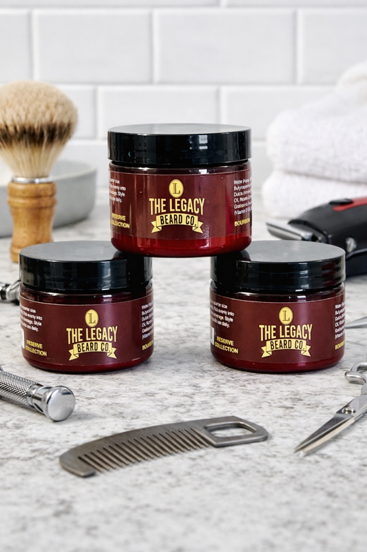 Three jars of 'The Legacy Barbers' product on a bathroom counter with grooming tools.