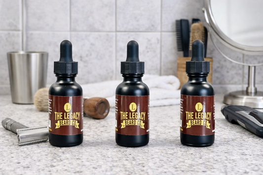 Three bottles of 'The Legacy Beard' product on a bathroom counter with grooming tools in the background.