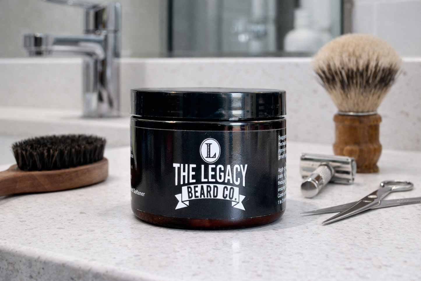 Black jar with 'The Legacy Beard Co.' logo on a bathroom counter with grooming tools.